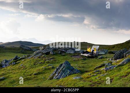 Mother and son sitting on wooden bench, having a good time outdoors on mountain with a view over the lake, Granattor, Lammersdorf Mountain, Austria Stock Photo