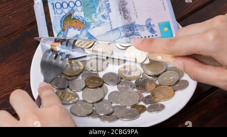 Cut off piece of money in a plate with a knife. Tenge, Kazakhstan. Concept, living wage. Economy, Central Asia. Sawing the budget, dividing, corruptio