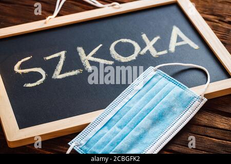 The inscription on the school board in Polish, Szkola and a question mark and an anti-virus mask. Stock Photo