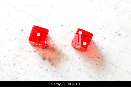 Two red craps dices showing Ace Deuce (Number 1 and 2) overhead shot on white board Stock Photo