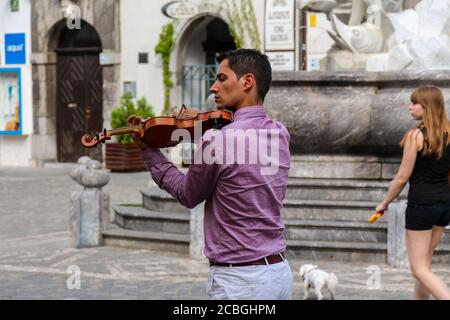Ljubljana, Slovenia - July 16th 2018: A violinist playing in Mestni Trg, Ljubljana Town Square beside the Robba fountain Stock Photo