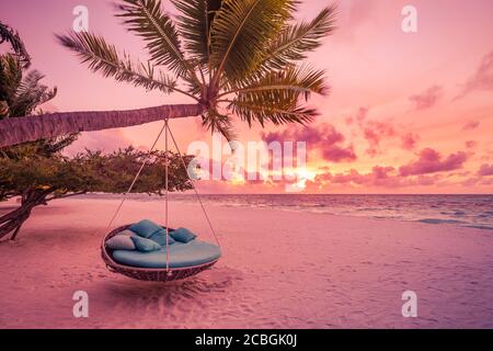 Tropical sunset beach background as summer landscape panorama with beach swing or hammock and white sand calm sea sky beach banner. Amazing beach view Stock Photo