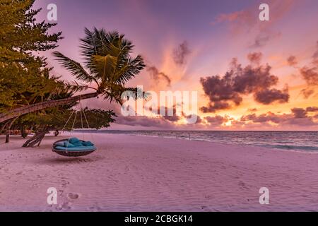 Tropical sunset beach background as summer landscape panorama with beach swing or hammock and white sand calm sea sky beach banner. Amazing beach view Stock Photo