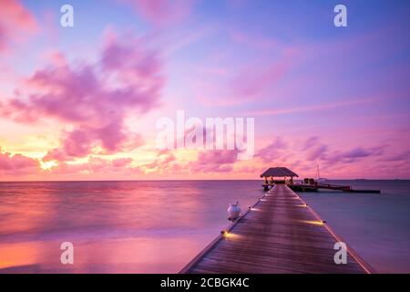 Maldives island sunset. Water bungalows resort at islands beach. Indian Ocean, Maldives. Beautiful sunset landscape, luxury resort and colorful sky.