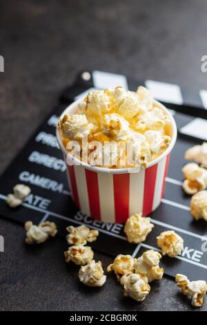 Sweet popcorn in cup and clappeboard on black table. Stock Photo