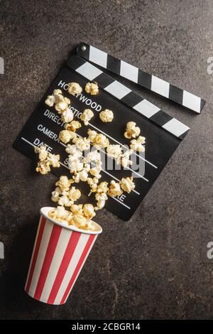 Sweet popcorn in cup and clappeboard on black table. Top view. Stock Photo