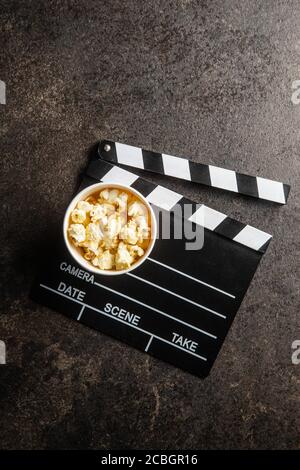 Sweet popcorn in cup and clappeboard on black table. Top view. Stock Photo