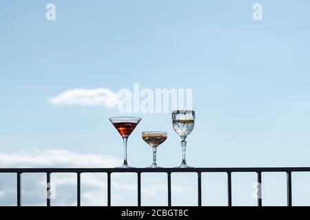 Still life of alcoholic drinks in cocktail glasses and wine glasses on a hot summer day under a blue sky Stock Photo