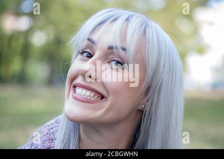 Outdoors portrait of a woman making funny faces. Silver hair. Stock Photo