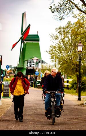 Hague, Netherlands 05/16/2010: People walking and cycling at a popular tourist spot in the Hague where traditional vintage Dutch Windmills (seen blurr Stock Photo