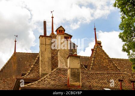 Close up isolated image of a complex traditional roof structure on a historic swiss building. Hexagonal clay tiles cover the steep slope of the roof w Stock Photo