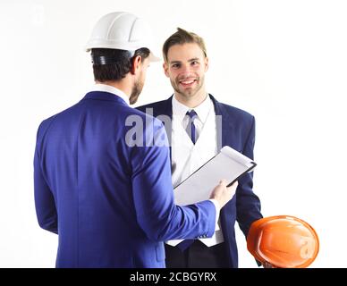 Entrepreneur and engineer with plans and smartphone. Construction, business people, engineering, business, building, design concept. Engineers with cheerful faces. Architects think about project. Stock Photo