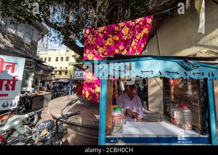 Bhopal, Madhya Pradesh,India - March 2019: An Indian street vendor at his roadside stall with a colourful curtain at the back. Stock Photo