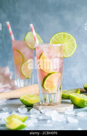 Fresh cocktail with lime and grapefruit juice. Paloma cocktail. There are two glasses on the table and they have environmentally friendly paper straws Stock Photo