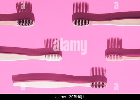 Wooden toothbrushes with shadows on a pink background. Dental concept. Stock Photo