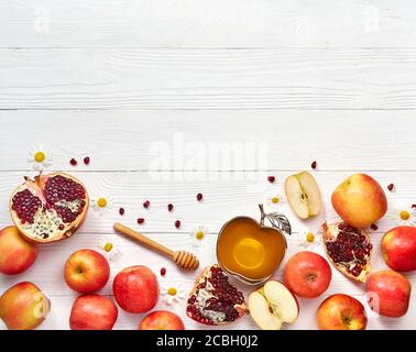 Rosh hashanah (jewish New Year holiday) concept. Traditional symbols. Apples, honey and pomegranates on a white wooden background. Stock Photo