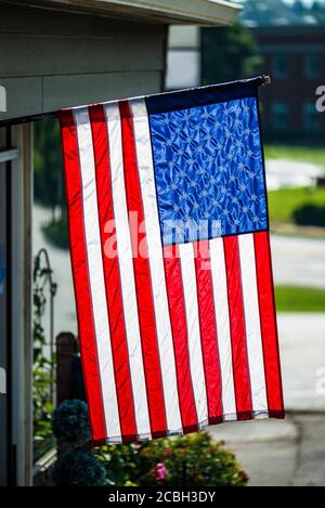 Vertical shot of an American Flag hanging vertically in front of a business. Stock Photo