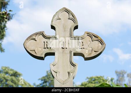 stone cross in front of a cloudy sky on a historical cemetery in germany Stock Photo