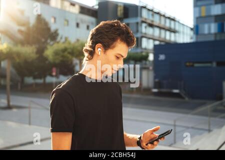 Handsome Caucasian man using mobile phone on sidewalk in city Stock Photo