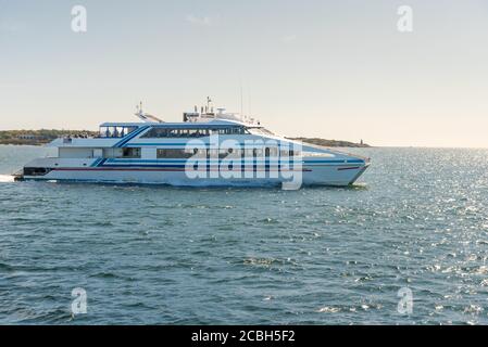 High-speed passenger ferry leaving a harbour on a sunny autum day Stock Photo