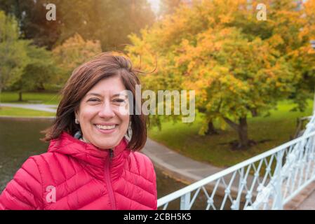 Portrait of a smiling woman in a park in autumn. Fall colors in background. Concept of hapiness. Stock Photo