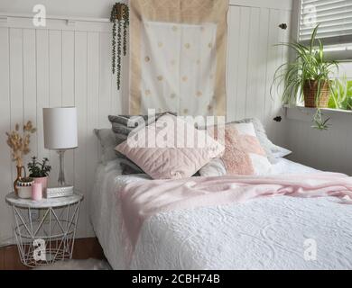 white and pink bedroom setting with cushions and bedside table Stock Photo