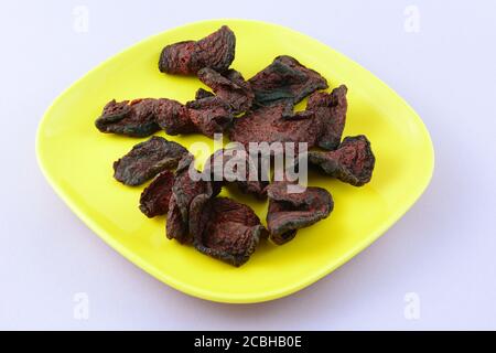 Organic red beet chips on yellow snack plate on lavender background Stock Photo