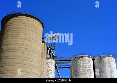 Watseka, Illinois, USA. Old grain elevators straddling a double track railroad mainline in a small north central Illinois community. Stock Photo