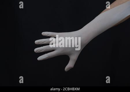Hand in protective glove on a black background. gesturing hand in white medical glove Stock Photo