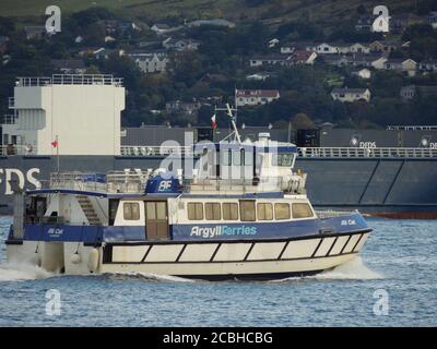 The container vessel Lysblink Seaways, and the passenger ferry Ali Cat, pass Gourock on the Firth of Clyde. Stock Photo