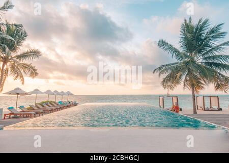 Umbrella and chair around infinity swimming pool near sea ocean beach at sunrise or sunset time. For leisure travel and vacation concept summer resort Stock Photo