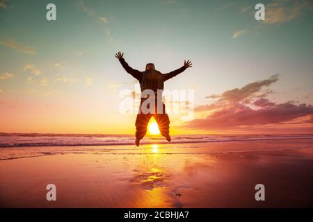 Jumping man on sunset beach Stock Photo