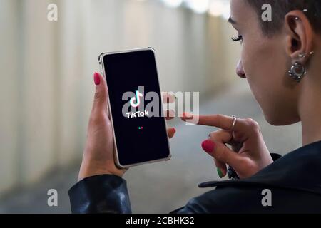 Women holding Phone with TikTok logo on the screen. Tik Tok is app to create and share videos Stock Photo