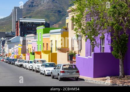 Cars parked outside colourful cottages in Wale Street in Bo Kaap, a district formerly known as the Malay Quarter, in Cape Town Stock Photo