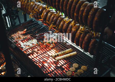 Smoked sausage hanging over the grill. The process of Smoking sausage. Cooking street food on the grill. Stock Photo