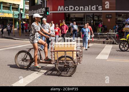 Cebu / Philippines - July 10, 2019: young Filipino man transporting container by tricycle on street in front of McDonalds Stock Photo