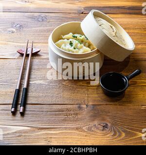 Japanese gyoza or dumplings snack with soy sauce in wooden steamer on wood japan table side view. Stock Photo