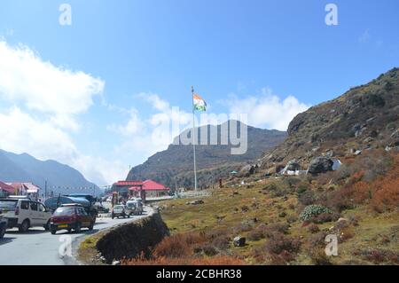 Cars lined up near Baba Harbhajan Singh Sahib Mandir in Nathu La with Indian Flag flying high, selective focusing