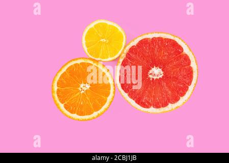 Halves of orange, pink grapefruit and lemon on pink background. Top view of cross section of citrus fruits. Minimal composition. Close-up Stock Photo