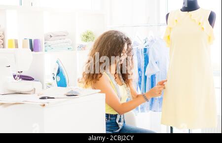 Lovely needlewoman adjusting dress on dummy in workshop Stock Photo