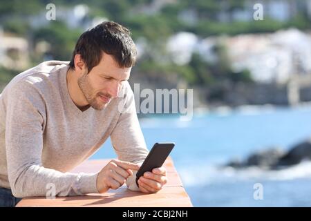 Serious man using smart phone on the beach in spring Stock Photo