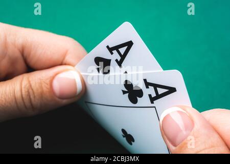 Two aces in girl hand on green felt background, close up view Stock Photo