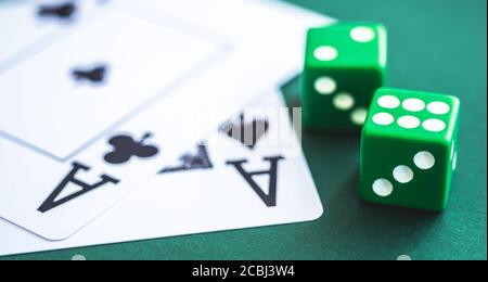 Green dice and playing cards on poker table Stock Photo