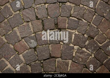 Stonework of wall or road. Dark granite stones are laid out in semicircle shape and filled with cement mortar. Close up shot. Abstract texture or Stock Photo
