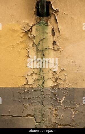 Cracks in old plastered wall. Black hole in wall of retro building or house with cracked plaster. Grunge concept