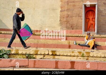 A boy walks with a kite in his hand crossing the Ganges ghat in Varanasi.Incidentally there is an ancient Hanuman temple. Stock Photo