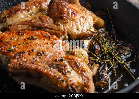 Barbecue Pork Chops on the bone with seasonings and grilled on hot skillet with smoke just from the fire close up side view. Stock Photo