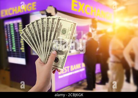 people, withdrawal, saving, finance, currency conversion and money exchange concept - hands with US dollar money with blur exchange booth background Stock Photo