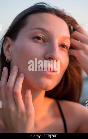Brunette touching face and looking away Stock Photo