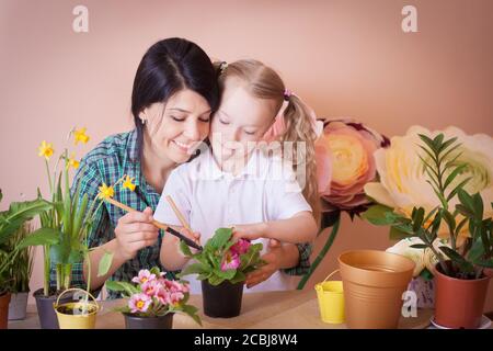 Cute child girl helps her mother to care for plants. Stock Photo